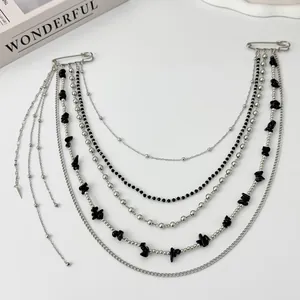 Detail showing multi-layer tassel chains with black stones and silver safety pins