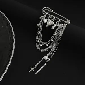 Detail view of punk silver heart pin with rhinestone star tassels and white pearls