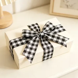 Close-up of a cream gift box featuring a classic black and white plaid ribbon bow