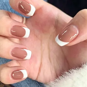 Macro detail of French tip press-on nails in cinnamon nude and classic white tips