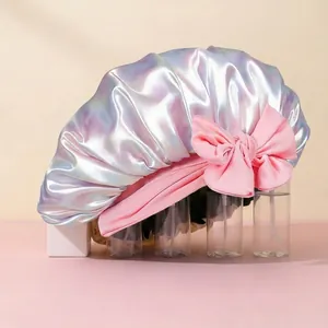 Detail of holographic satin hair bonnet featuring a large pink bow and elastic band