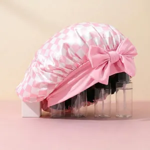 Detailed texture of pink and white checkered satin sleep cap with a large decorative bow