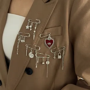 Detail of silver safety pin brooch with heart and star charms on a brown blazer
