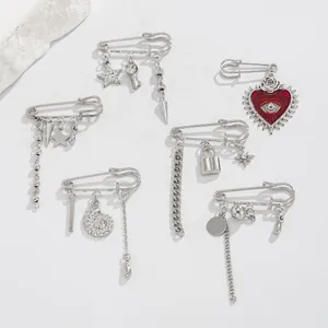 Detailed silver pins with heart and moon pendants including metal tassels on white rock