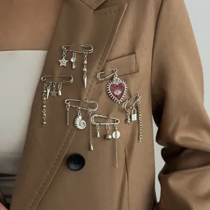 Silver gothic brooch pins set with heart and star pendants on a brown suit lapel