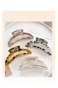 Detail of four acetate moon crescent hair claws in marble and tortoiseshell patterns