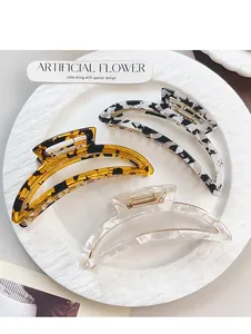 Detailed view of three resin hair claw clips in tortoiseshell and marble patterns on a white plate