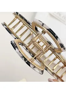 Macro shot of gold metal hair claw with black and white marble pattern plates