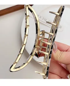 Close-up of golden crescent hair claw with black and white spotted acetate panel