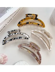 Detailed close-up of four acetate crescent hair claws with diverse marble and amber patterns