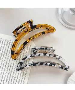 Close-up of crescent hair claws in amber tortoiseshell and black white marble patterns