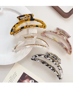 Detail of four patterned hair claws including amber and marble designs on a ceramic plate