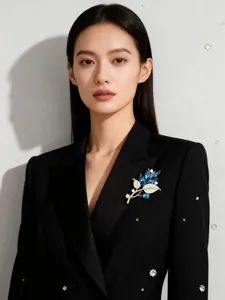 Elegante blaue Blattbrosche mit Kristallakzenten auf einem schwarzen Blazer-Jackett