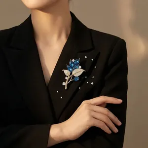 Eleganter goldener Blatt-Anstecker mit blauen Kristallen auf einem schwarzen Revers