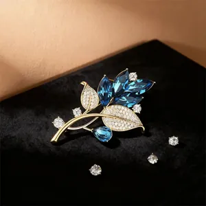 Eleganter Blatt-Brosche in Gold mit tiefblauen Kristallen und funkelnden Diamant-Akzenten