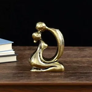 Detailed view of abstract gold brass kissing couple sculpture on wooden desk