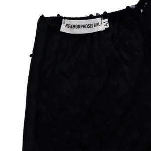 Detail of sequin trim, side zipper, and size M brand label on black dress fabric
