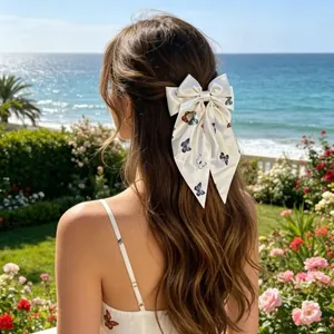 Nœud à cheveux élégant en satin blanc avec imprimés papillons colorés sur longs rubans