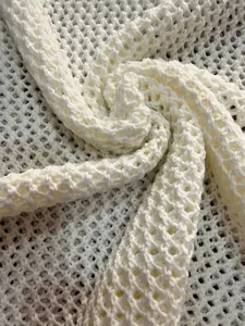 Detailed macro view of white crochet knit fabric with wavy hollow-out mesh texture