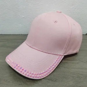 Close-up of pink cotton baseball cap featuring shiny rhinestones on the brim and embroidery
