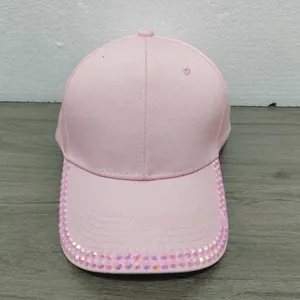 Detailed close-up of pink cotton baseball cap featuring shiny rhinestones on the brim
