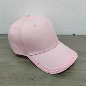 Close-up of pink baseball cap featuring sparkling rhinestones on the brim detail