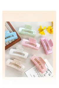 Macro shot of macaron-colored grid pattern hair claw clips on a minimalist aesthetic desk