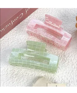 Close-up of pink and green square hair claws with elegant white grid patterns