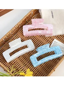 Close-up of three colorful pearlescent PVC hair claws with mosaic texture on a tray