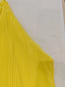 Close-up of vibrant yellow pleated dress showing high-density vertical folds and fabric texture