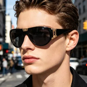 Close-up of black aviator sunglasses with gold logo detail and dark grey lenses on model