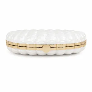 Detailed view of pearlescent white acrylic shell clutch bag with gold metallic frame