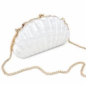 Macro detail of white shell evening bag with gold metal trim and pearl-like texture