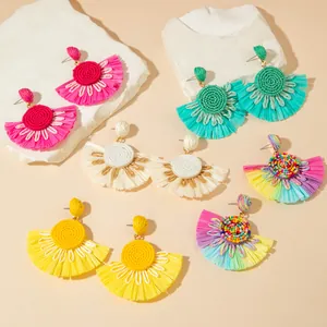 Detail of bohemian raffia fan earrings in multiple colors for vacation style jewelry