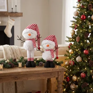 Detail of plush Christmas snowmen with striped hats on wooden table in festive room