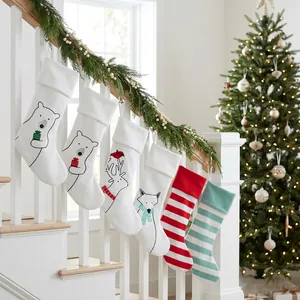 Set of plush Christmas stockings with polar bear and reindeer embroidery on stairs
