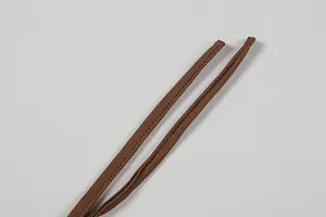 Detail of brown thin straps on a satin knit dress showing fine stitching and texture