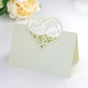 Macro shot of laser cut pearl white place card with Only Love heart design for wedding