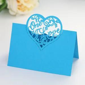 Detail of sky blue laser-cut One Love heart wedding place card on white surface