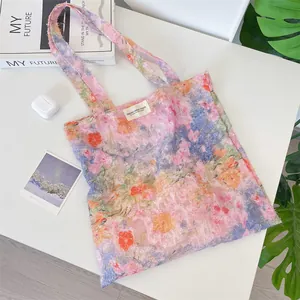 Detail of floral canvas tote bag with woven brand label and textured lace fabric