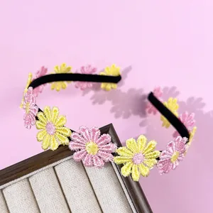 Primo piano dettagliato di margherite ricamate rosa e gialle su un cerchietto nero