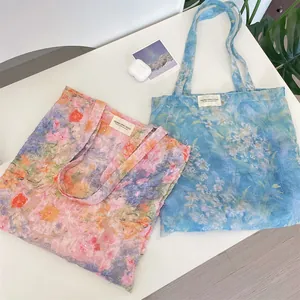 Detail view of floral lace tote bags with 3D feather texture and brand labels
