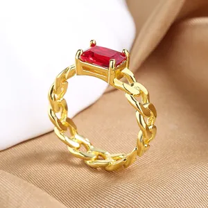 Macro detail of gold-toned chain ring featuring a rectangular red zircon in 4-prong setting