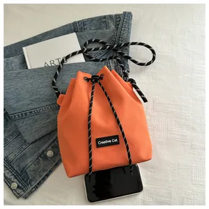 Dettaglio vista dall'alto di una borsa a secchiello arancione con coulisse e logo