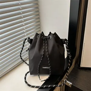 Dettaglio di un secchiello in nylon nero con tracolla in corda intrecciata a righe