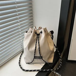 Dettaglio della borsa a secchiello off-white con coulisse a pois ed etichetta tessuta
