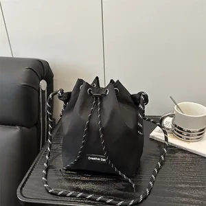 Dettaglio borsa a secchiello nera con coulisse, etichetta Creative Cat e tracolla