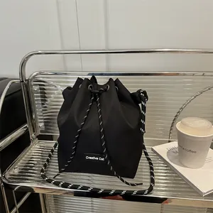 Dettaglio della borsa a secchiello nera con coulisse, etichetta Creative Cat e tracolla