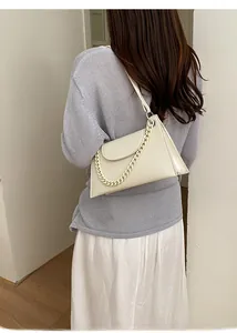Detail of cream white leather baguette bag with thick chain strap worn by a model