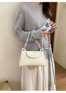 Detail of cream white chain handbag worn by model with minimalist grey knitwear